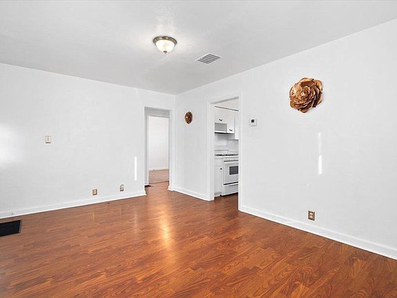 An empty living room with hardwood floors and white walls.