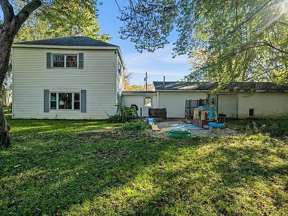 A large white house with a playground in the backyard.