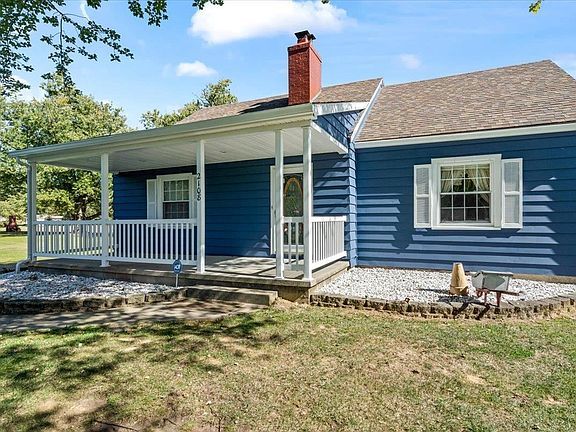 A blue house with a white porch and a red chimney.