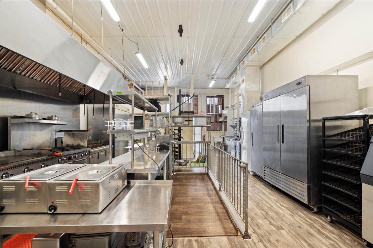A long kitchen with a lot of stainless steel appliances.