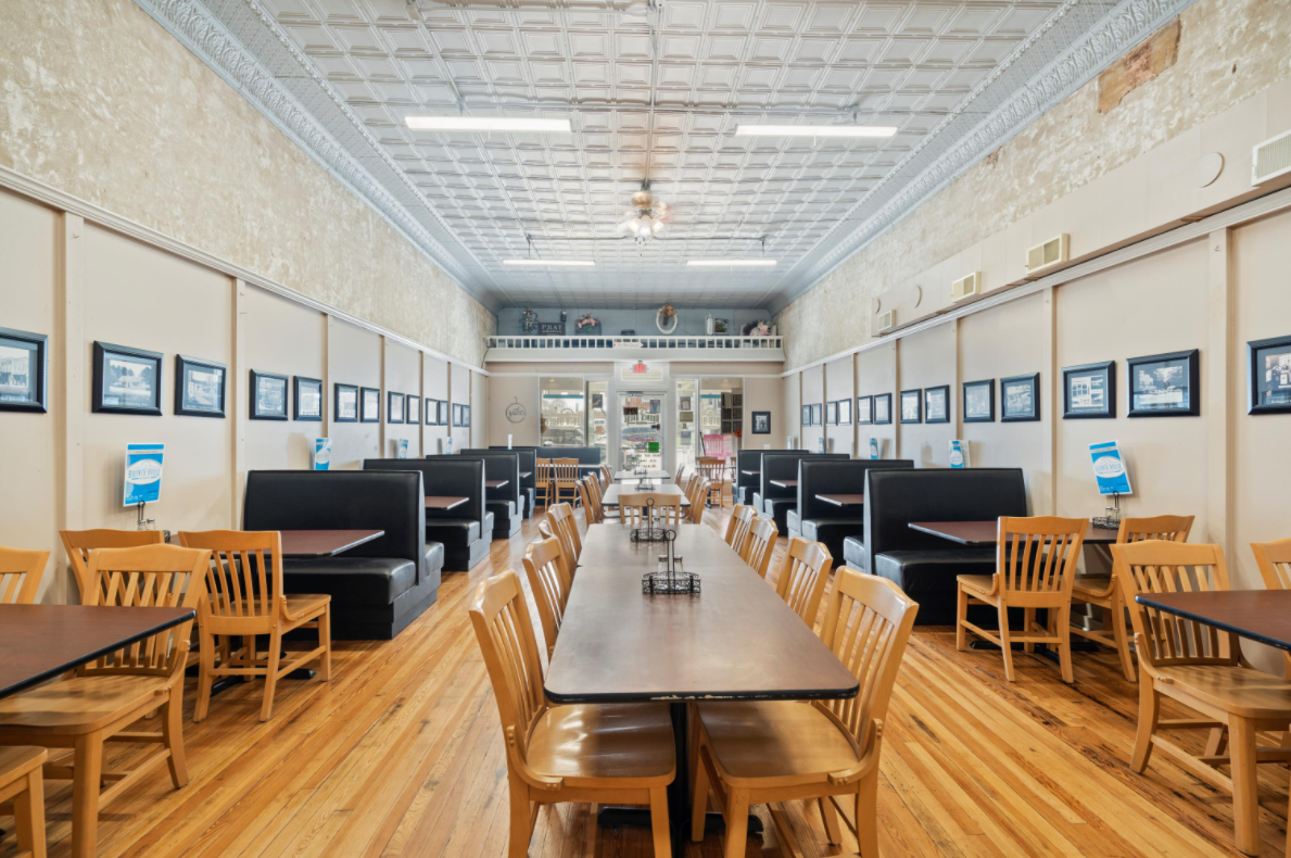 A long room with tables and chairs in a restaurant.