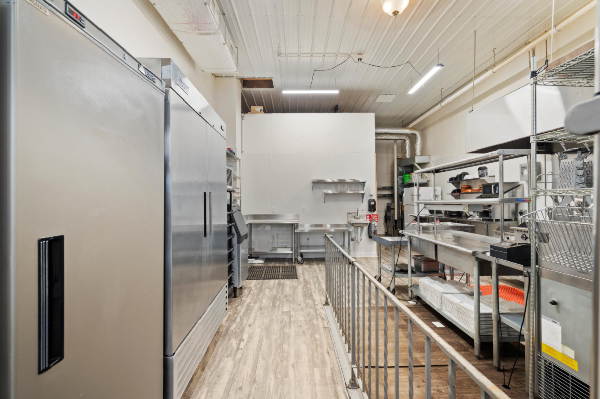 A kitchen with a lot of stainless steel appliances and a long hallway.