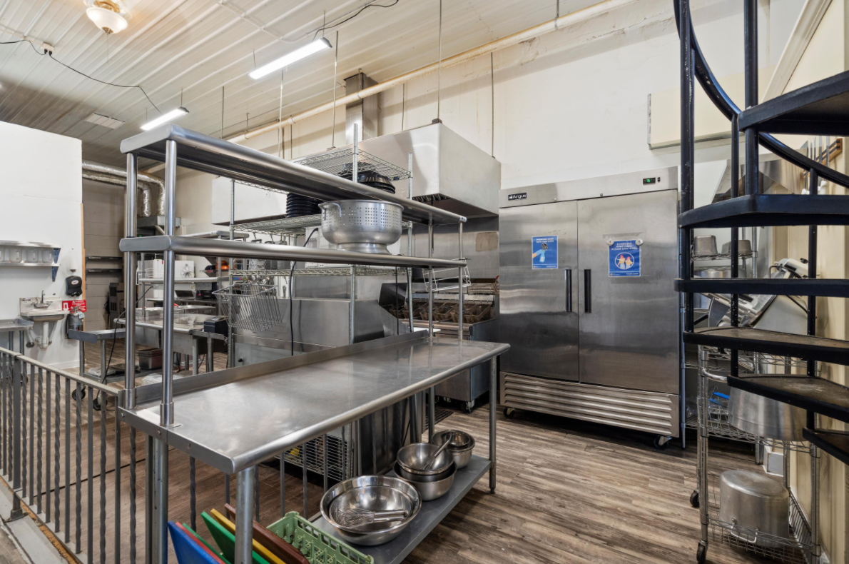 A large kitchen with stainless steel appliances and a spiral staircase.