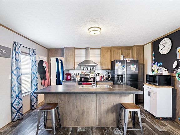 A kitchen with a large island , sink , refrigerator and microwave.
