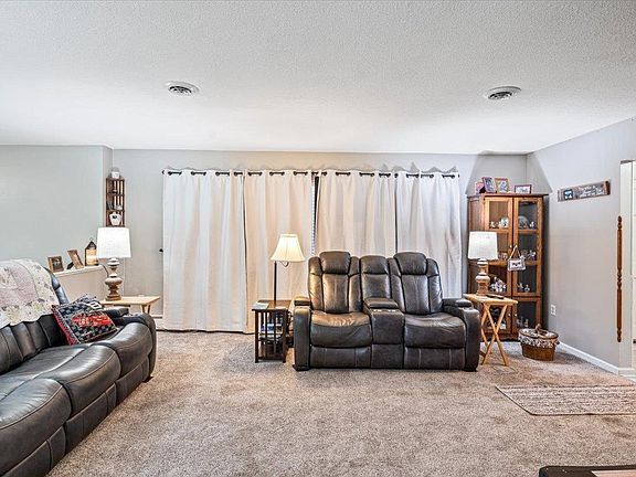 A living room with a couch , chairs , lamps and curtains.