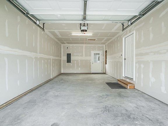 An empty garage with a garage door open and a white door.