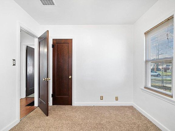 An empty bedroom with a wooden door and a window.