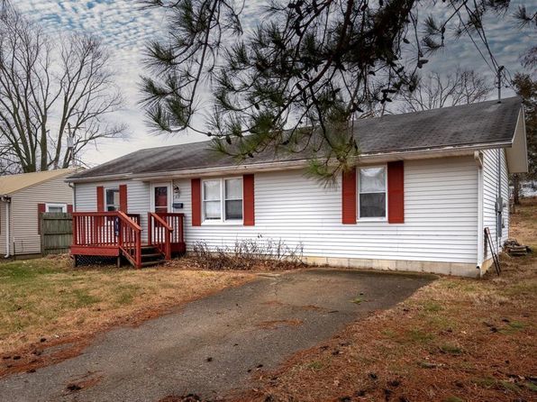 A white house with red shutters and a red deck.