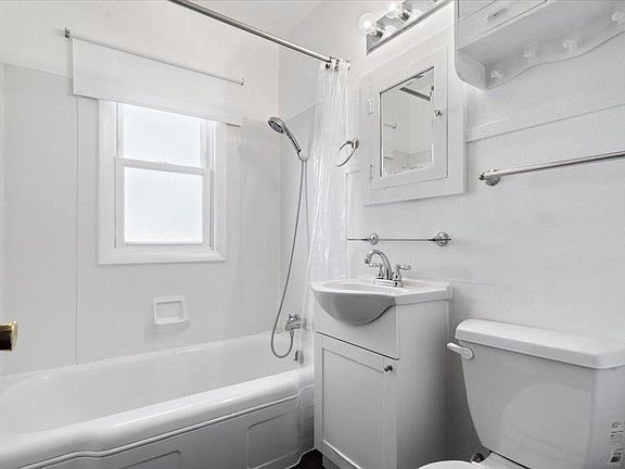 A bathroom with a tub , sink , toilet and mirror.