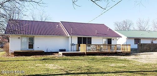 A white house with a red roof and a wooden deck.