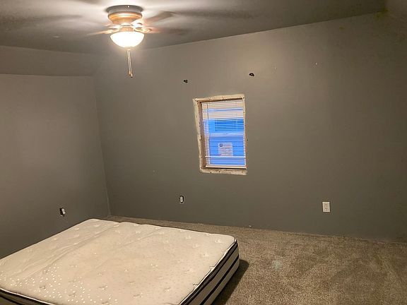A bedroom with a bed , ceiling fan , and window.