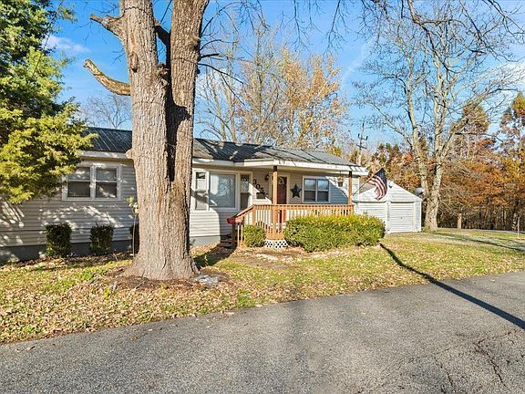 A white house with a large tree in front of it.
