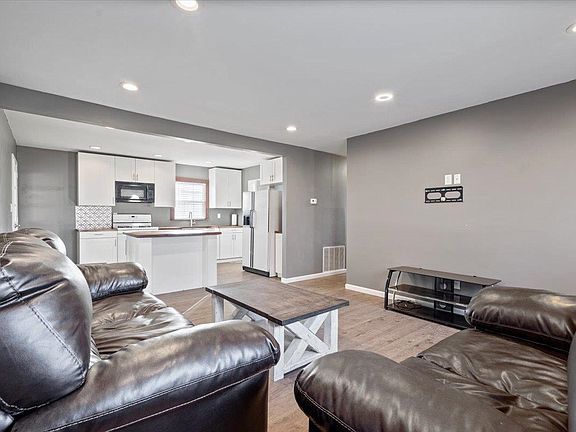 A living room with two couches , a coffee table , and a kitchen.