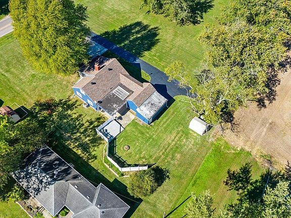 An aerial view of a house in a residential area surrounded by trees.