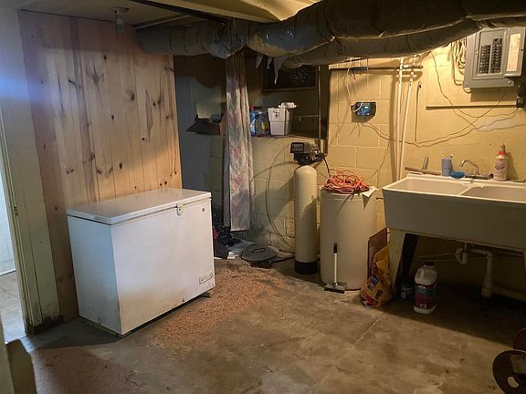 A basement with a sink , freezer , and water heater.