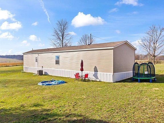 A mobile home is sitting in the middle of a grassy field.