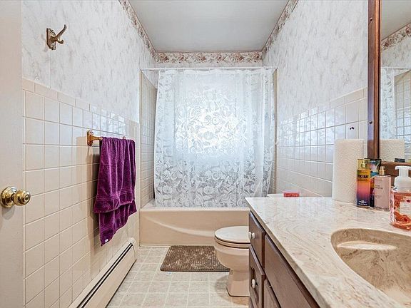 A bathroom with a toilet , sink , shower and mirror.