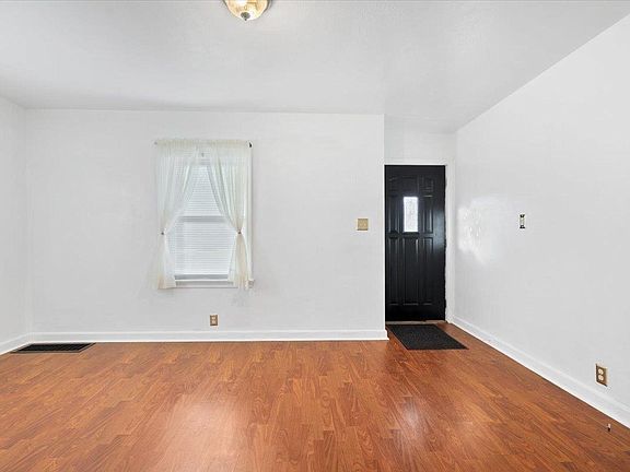 An empty living room with hardwood floors and a window.