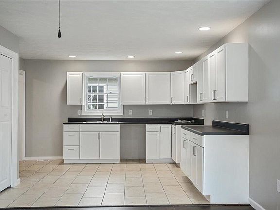 An empty kitchen with white cabinets and a window.
