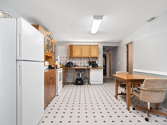 A kitchen with a table and chairs and a refrigerator.
