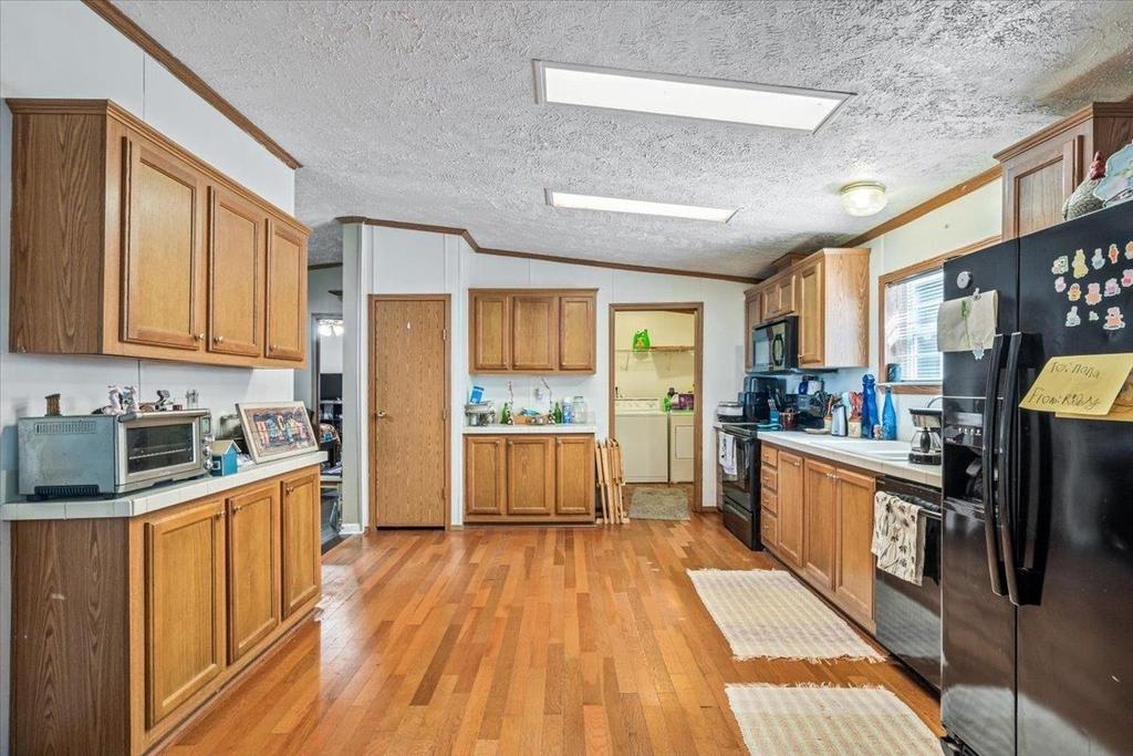 A kitchen with wooden cabinets , stainless steel appliances , and a black refrigerator.