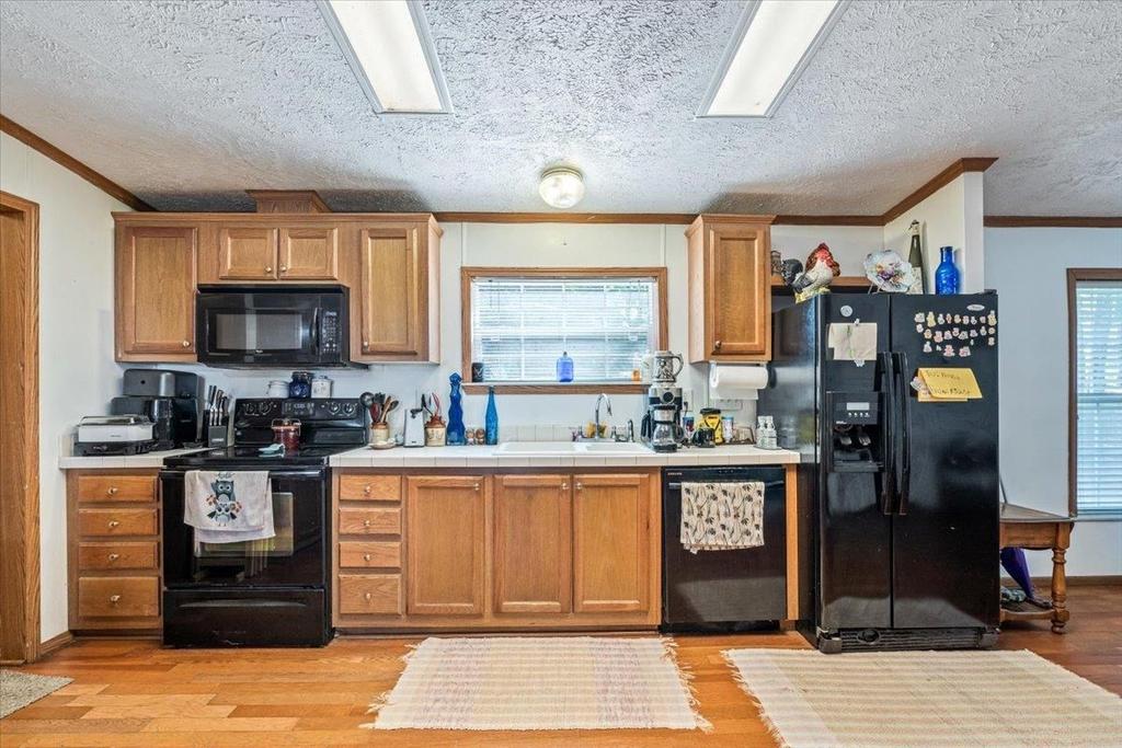 A kitchen with wooden cabinets and a black refrigerator