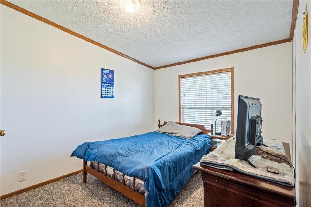 A bedroom with a bed , dresser , and television.