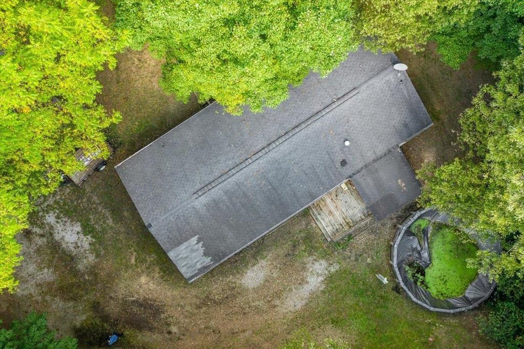 An aerial view of a house in the middle of a forest surrounded by trees.