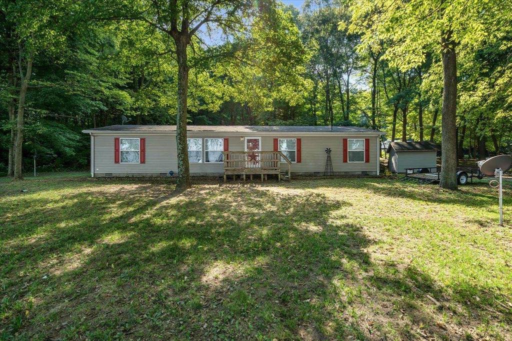 A mobile home is sitting in the middle of a lush green field surrounded by trees.