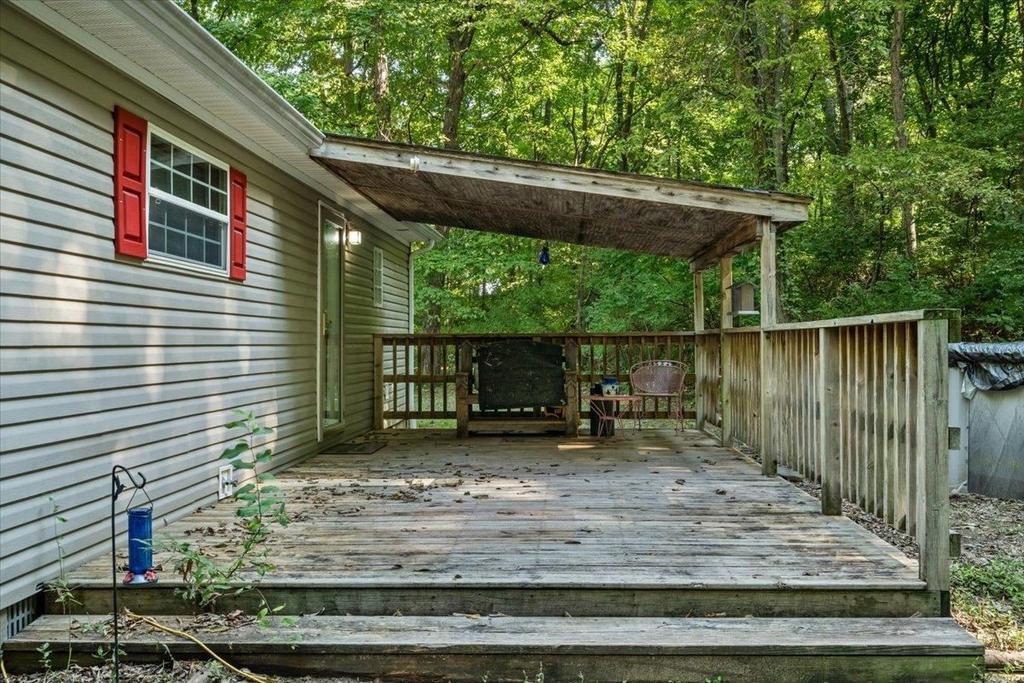 A mobile home with a large wooden deck in front of it.