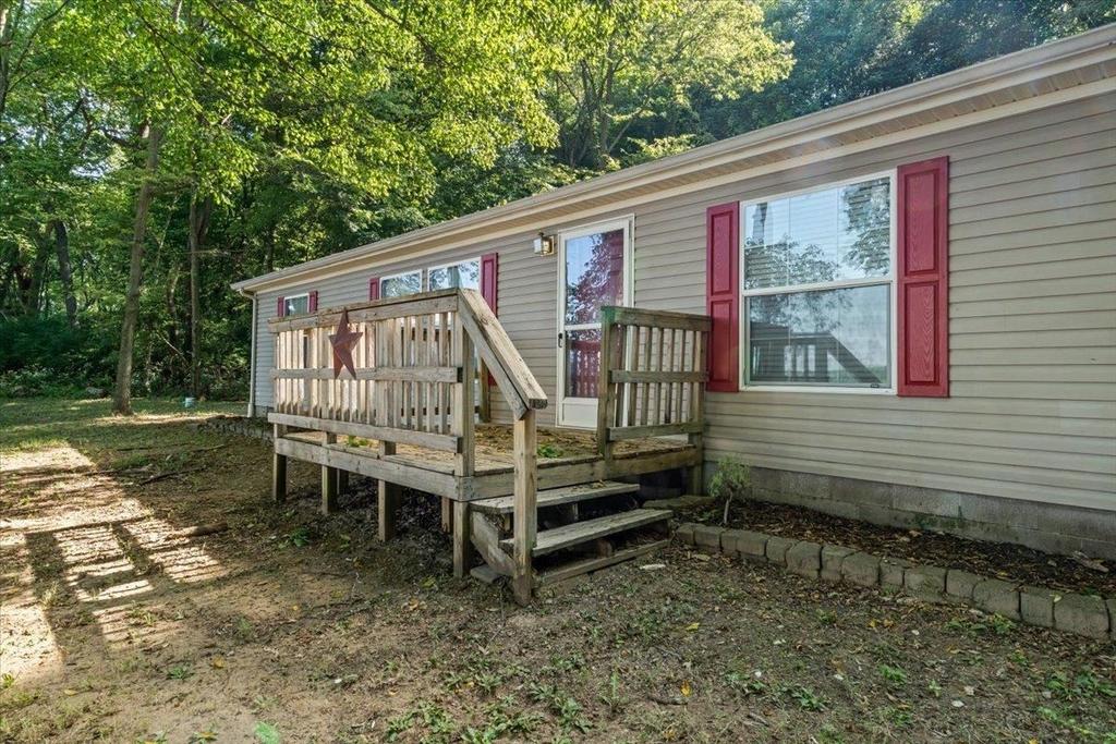 A mobile home with a deck and stairs in front of it.