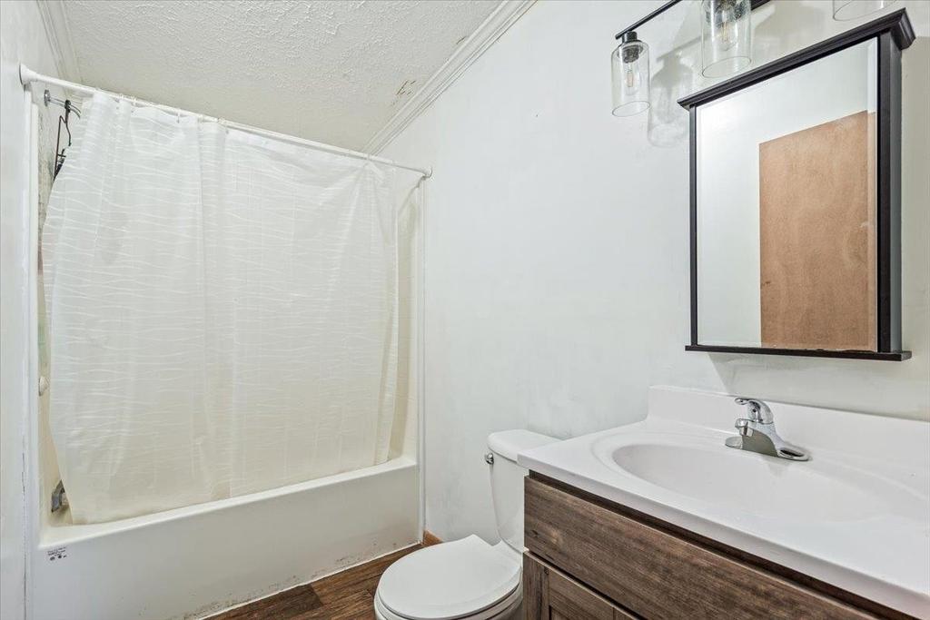 A bathroom with a toilet , sink , mirror and bathtub.