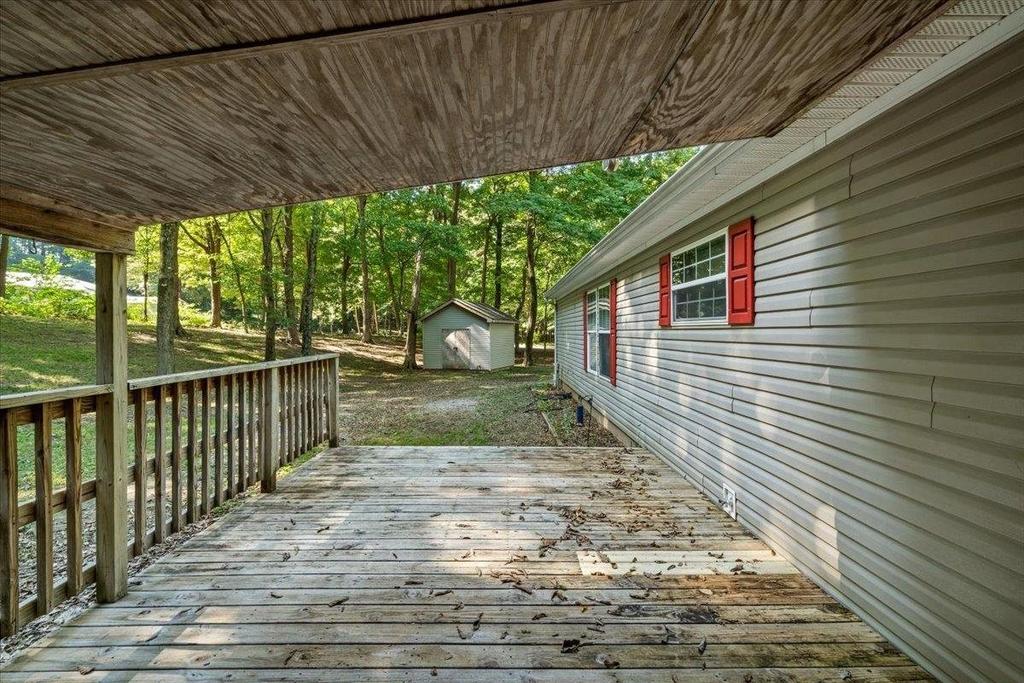 An empty wooden deck with a white house in the background.