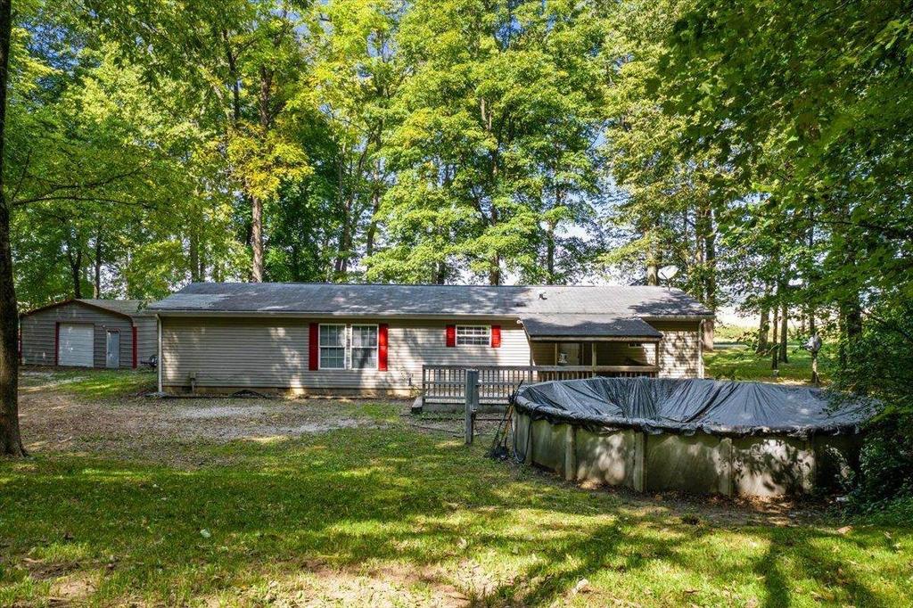 A house with a pool in the backyard is surrounded by trees.
