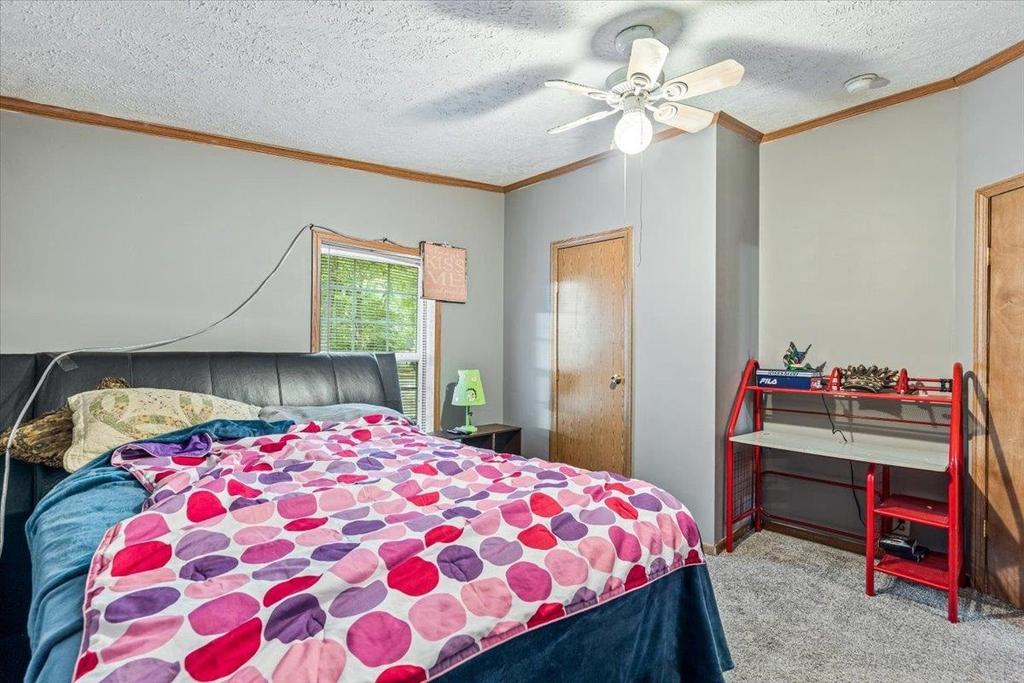 A bedroom with a bed , desk and ceiling fan.