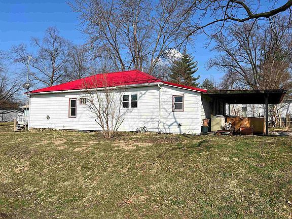 A white house with a red roof is sitting in the middle of a grassy field.