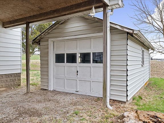 A white garage door is sitting under a covered porch next to a house.
