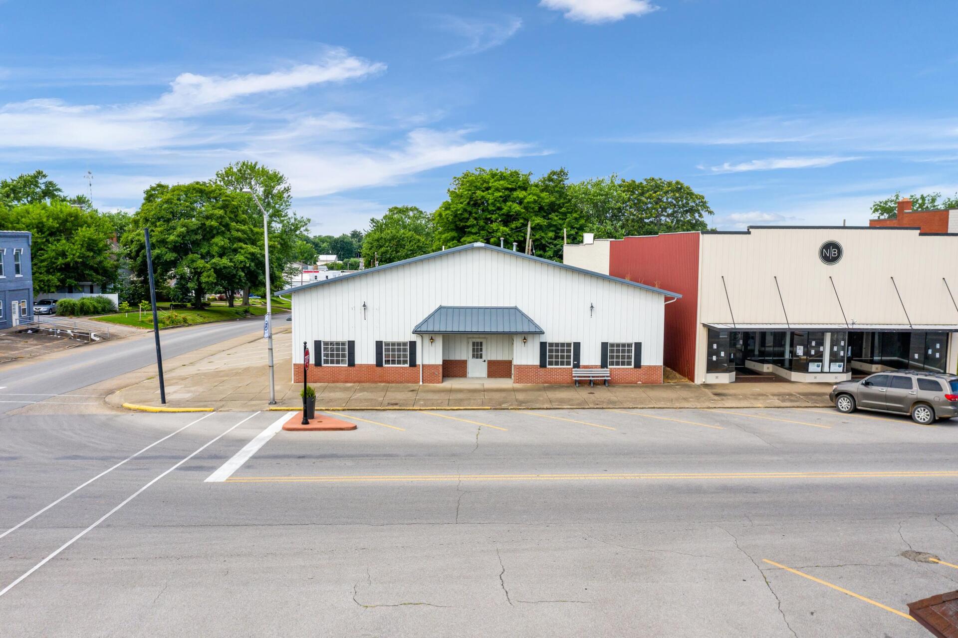 A large white building is sitting on the corner of a street.