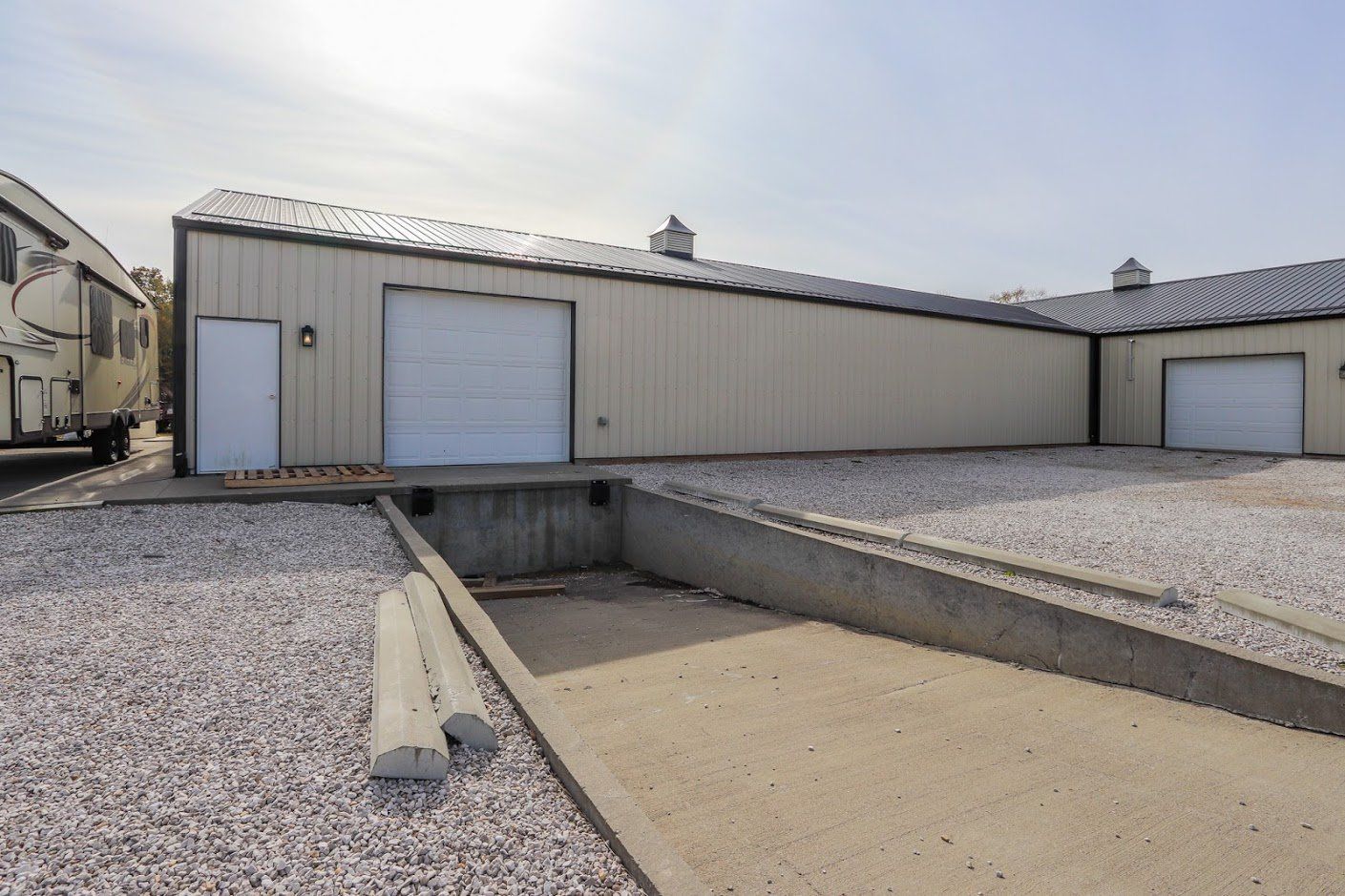 A building with a white garage door is surrounded by gravel