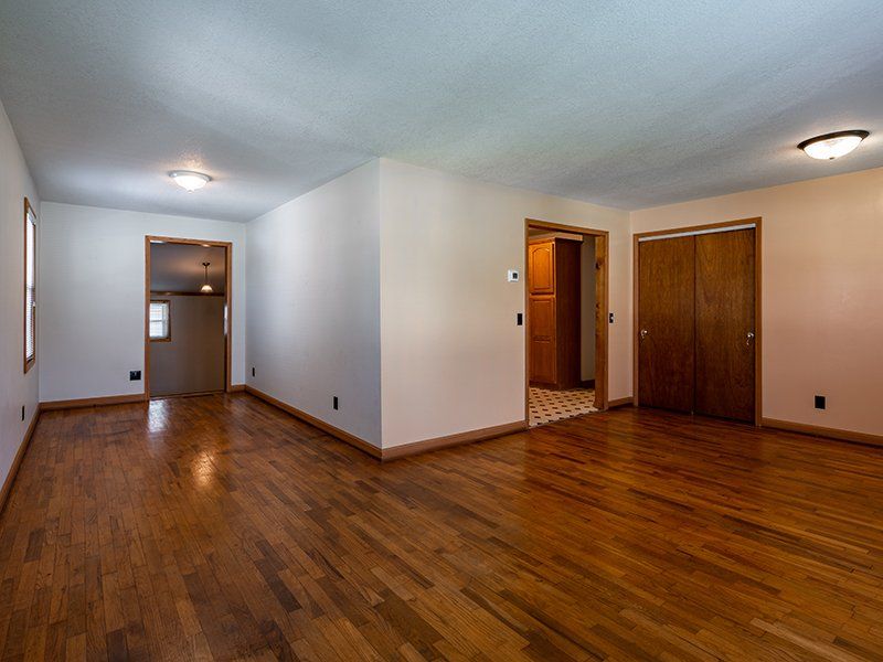 An empty living room with hardwood floors and white walls.