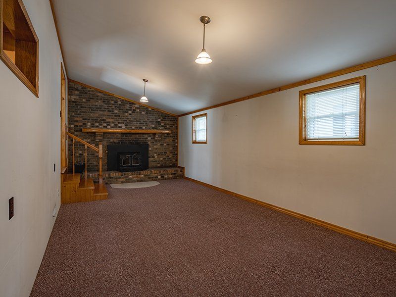 An empty living room with a fireplace and stairs.
