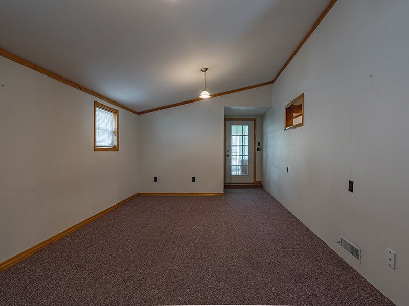 An empty room with a purple carpet and a window.