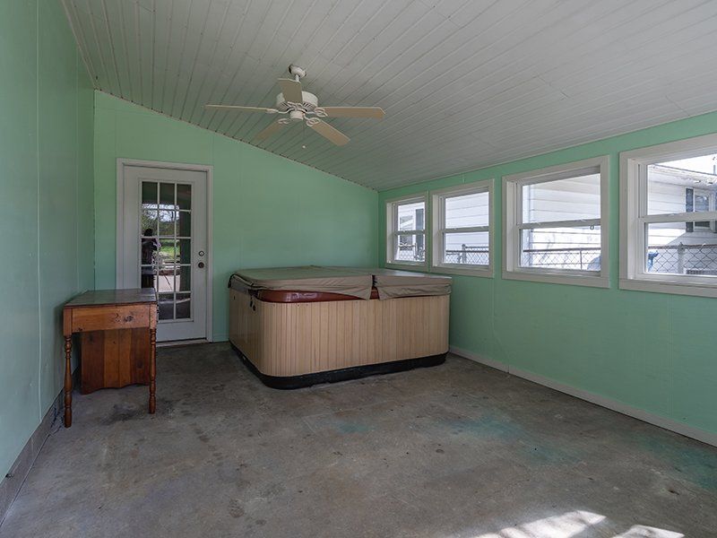 An empty room with a hot tub and a ceiling fan.