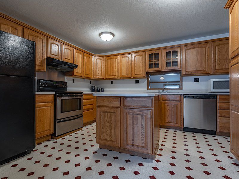 A kitchen with wooden cabinets , stainless steel appliances , and a black refrigerator.