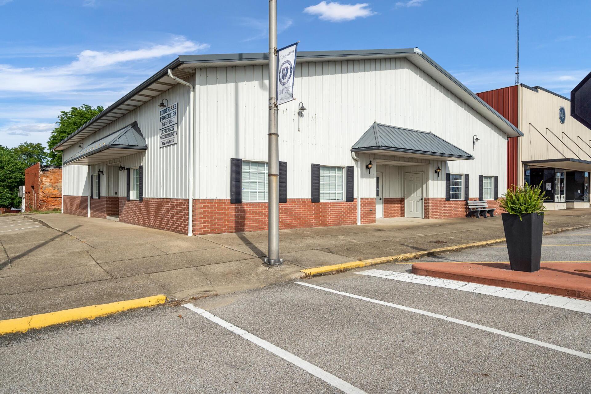 A large white building with a brick facade and a parking lot in front of it.