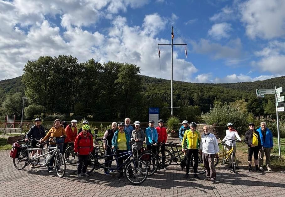 Tandem-Fahrradgruppe bei einer Rast an einem Aussichtspunkt mit Flusslandschaft.