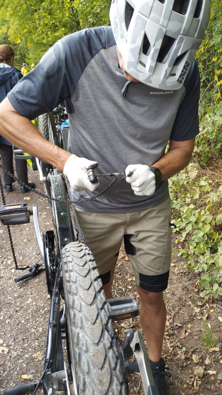 Person repariert die Kette eines Tandemfahrrads während einer Radtour.