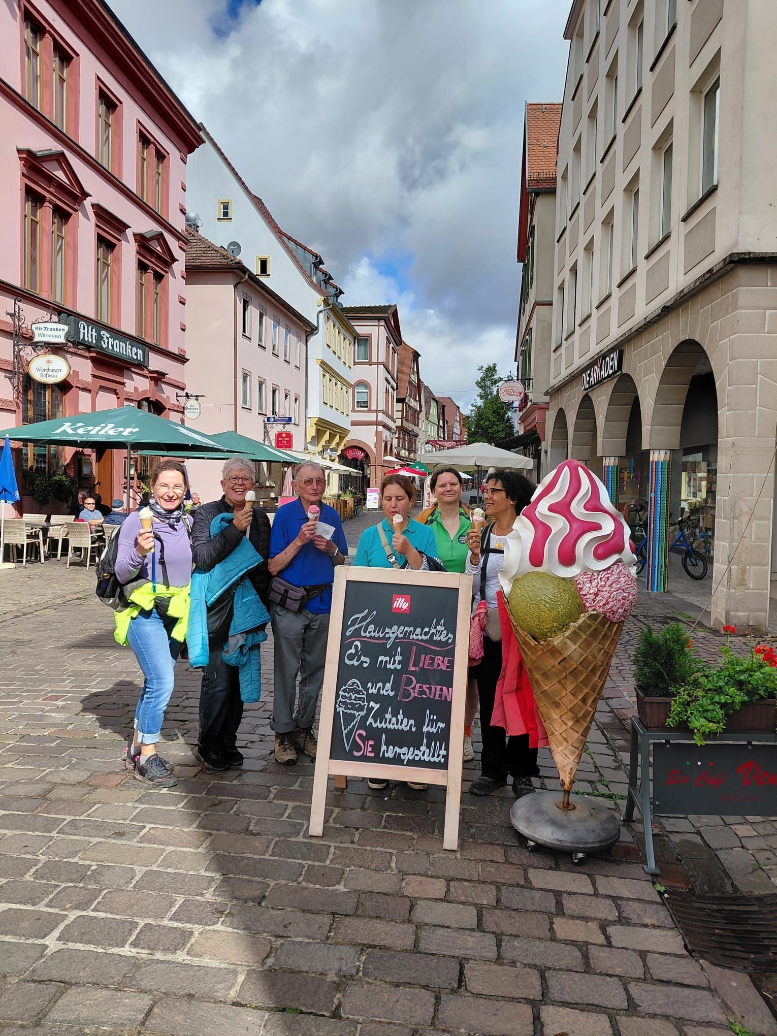 Ausflugsgruppe isst Eis in einer Altstadtstraße während einer gemeinsamen Tour.
