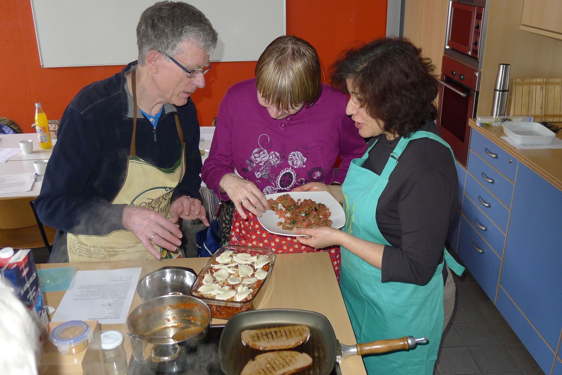 Ein Mann und zwei Frauen bereiten in einer Küche Essen zu