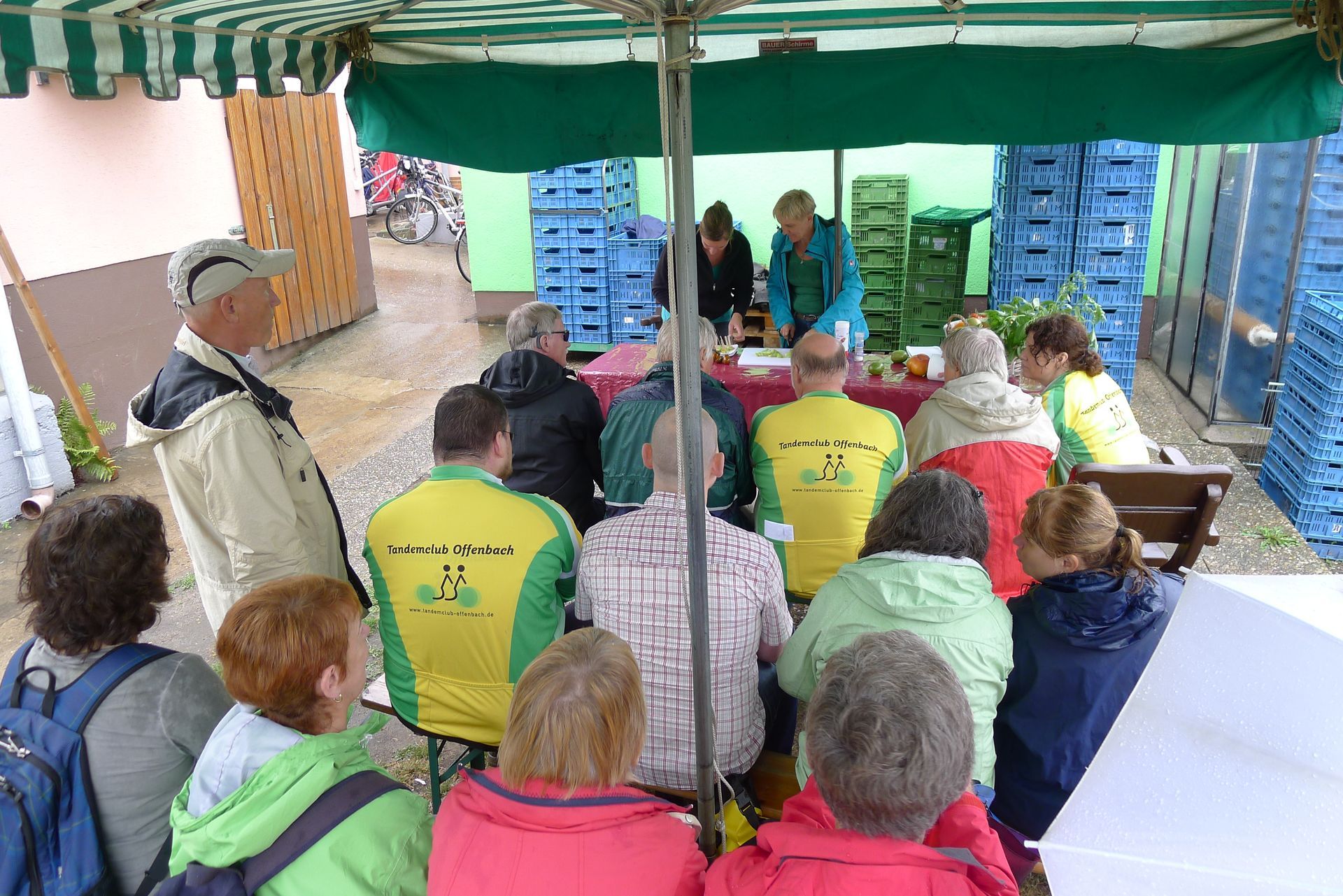 Eine Gruppe von Menschen sitzt vor einem Tisch unter einem Zelt.